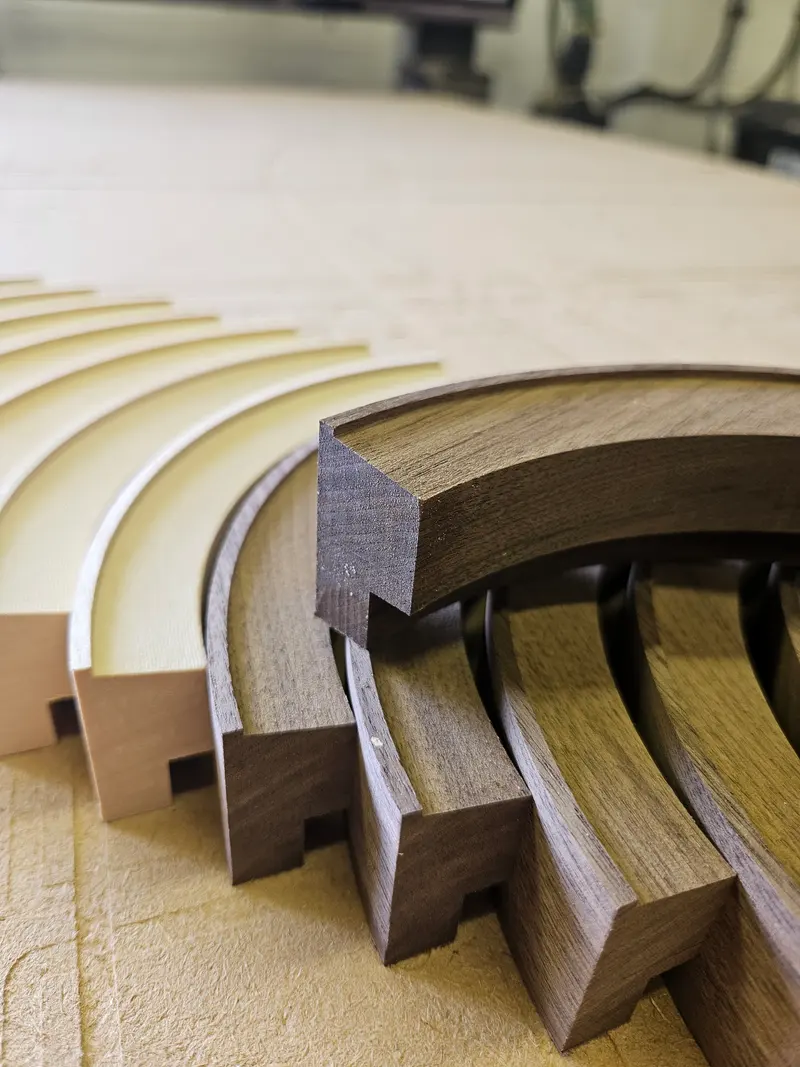 Curved hardwood sections laid out on the CNC bed