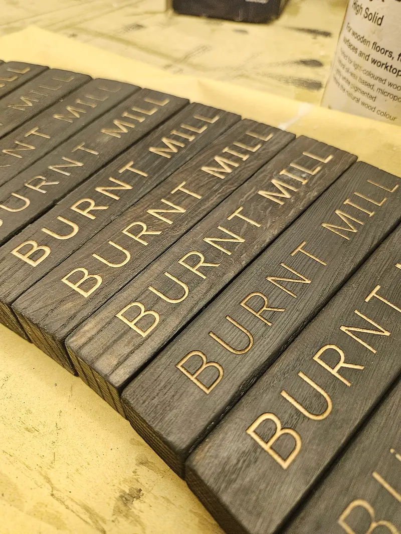 Row of dark timber pieces engraved with a brewery name